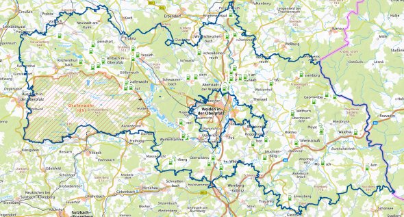 Karte des Landkreises Neustadt an der Waldnaab und umliegender Regionen mit Markierungen für E-Ladesäulen. Grüne Symbole markieren Standorte von Ladestationen für Elektrofahrzeuge im Landkreis.