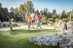FREU.ZEIT für Kinder
© Oberpfälzer Wald, Fotograf Thomas Kujat Eine Familie spielt gemeinsam Minigolf auf einem sonnigen Outdoor-Platz mit Kunstrasen, umgeben von Bäumen und Felsen. Zwei Kinder putten, während die Eltern zuschauen.