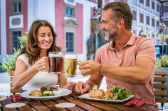 Gastronomie
© Oberpfälzer Wald, Fotograf Thomas Kujat Paar stößt mit Bierkrügen an einem gedeckten Tisch im Freien an, vor historischer Gebäudekulisse, mit traditionellen Gerichten.