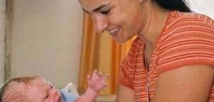 Hebamme mit einem Baby in der Hand.
